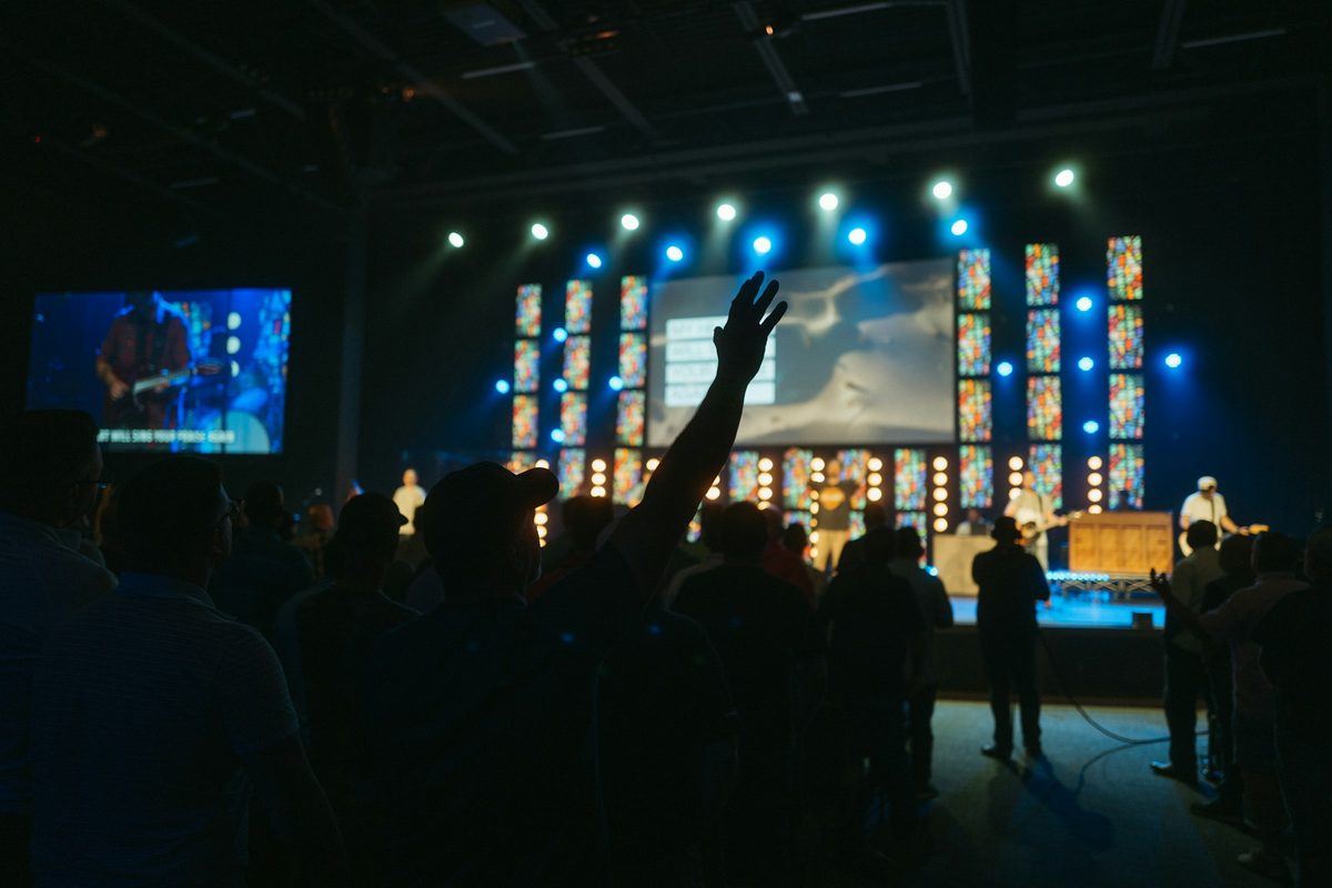 A stage framed by LED panels and lights, with a screen beside it for the back rows